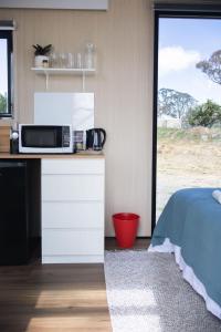 a kitchen with a microwave on a counter next to a bed at Beckford Tiny House 1 by Tiny Away in Good Hope