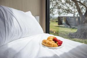 a plate of croissants and strawberries on a bed at Beckford Tiny House 1 by Tiny Away in Good Hope +18 photos