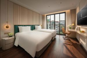 two beds in a hotel room with a large window at Luxeden Classic Hotel in Hanoi
