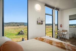 a bedroom with a bed and a view of a field at Clover at Lexington Park by Tiny Away in Tarlo