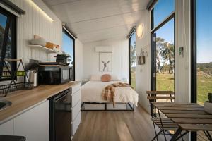 a kitchen with a bed in a small room with windows at Clover at Lexington Park by Tiny Away in Tarlo