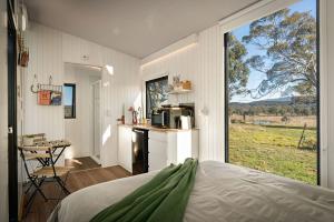 a bedroom with a bed and a kitchen with a large window at Myrtle at Lexington Park in Tarlo