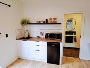 a kitchen with white cabinets and a black microwave at Guesthouse on Gardiners in Christchurch