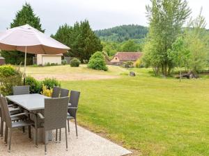 a table and chairs with an umbrella on a lawn at Lac Bleu Nr 38 in Lacapelle-Marival