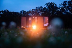 a small house with the lights on in a field at Gumnut by Tiny Away in Kangaroo Valley