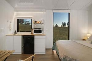 a bedroom with a bed and a kitchen with a microwave at The High Country Views Escape by Tiny Away in Table Top