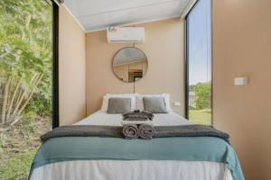 a bedroom with a bed with a large window at Hinterland Hideout by Tiny Away in Myocum