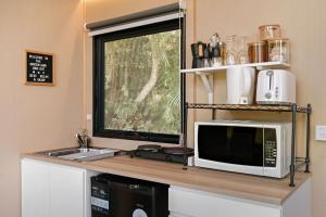 a kitchen with a microwave and a sink and a window at Hinterland Hideout by Tiny Away in Myocum