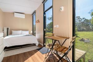 a bedroom with a bed and a table and a window at Huntingdon House by Tiny Away in Wauchope