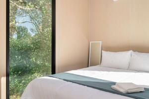 a bed in a room with a large window at Huntingdon House by Tiny Away in Wauchope
