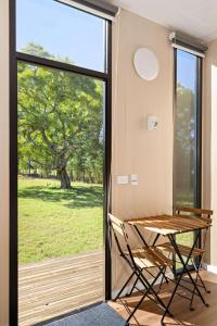 a table and chair in a room with a sliding glass door at Huntingdon House by Tiny Away in Wauchope +14 photos