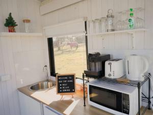 a kitchen with a microwave and a sink and a window at Little Argyle Tiny House by Tiny Away in Coonabarabran