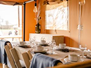 a table with plates and cups and glasses on it at Glamping Lodge in Westerland