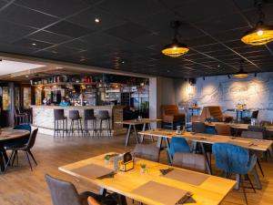 a restaurant with wooden tables and chairs and a bar at Wadden Lodge Living in Westerland