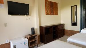 a room with a television and a bed and a dresser at Pousada Casa do Professor in Barreirinhas
