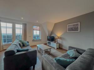 a living room with two couches and a tv at Waddenhuis in Westerland