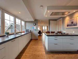 a kitchen with white cabinets and black counter tops at Waddenhuis in Westerland