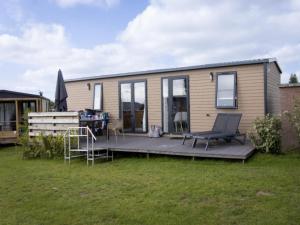a tiny house with a deck with a table and chairs at Wadden Lodge Plus in Westerland