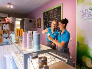 two people standing behind a counter in a restaurant at Wadden Lodge Plus in Westerland
