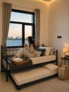 a woman sitting on a bed looking at her cell phone at Orchid Villa salalah in Salalah +216 photos