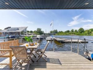 a wooden deck with a table and chairs on the water at Tiny Houseboat De Woudaap - I in Uitgeest