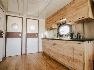 a kitchen with wooden cabinets and a white door at Tiny Houseboat De Woudaap - I in Uitgeest