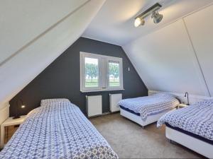 a attic bedroom with two beds and a window at Poldergeluk in Ooltgensplaat