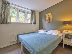 a bedroom with a bed with a blue blanket and two windows at Heidepracht in Putten