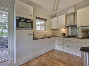 a kitchen with white cabinets and a large window at Heidepracht in Putten