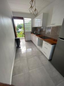 a large kitchen with white cabinets and a window at Grand appartement ventilé in Morne-à-lʼEau