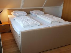 a white bed with two pillows on top of it at Graspieper in Zonnemaire
