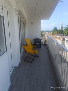 a balcony with a yellow chair and a table at Grand appartement ventilé in Morne-à-lʼEau +2 photos