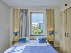 a bedroom with a bed with blue pillows and a window at SeaLuxe Residence 27C in Colijnsplaat