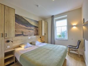 a bedroom with a bed and a chair and a window at Sauna Zee 27A in Colijnsplaat