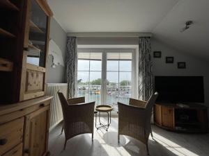 a living room with a table and chairs and a television at Panoramablick-Orther-Hafen-Fehmarn in Orth
