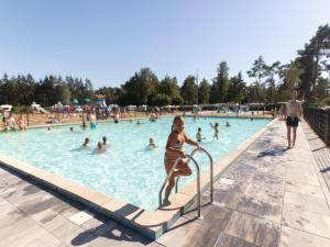 ein junges Mädchen im Badeanzug in einem Schwimmbecken in der Unterkunft Easy Chalet in Vessem