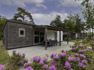 a modular house with a patio and flowers at Woodlodge XL 588 in Vessem