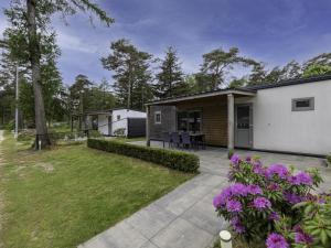 a home with a patio and yard with purple flowers at Woodchalet in Vessem