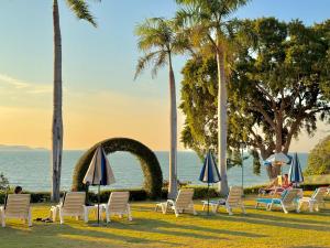 a group of chairs and umbrellas on the grass near the ocean at Asia Pattaya Hotel in Pattaya South