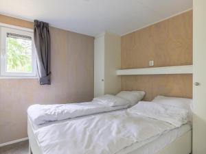 a bedroom with two beds and a window at Woodlodge XL 588 in Vessem +20 photos