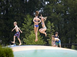 a group of children jumping on top of a swimming pool at Safaritent 6 in Vessem