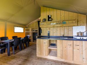 a kitchen with wooden cabinets and a table and chairs at Safaritent 6 in Vessem
