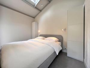 a bedroom with a large bed with white sheets at Quercus in Valkenswaard