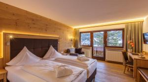 a hotel room with two beds and a desk and window at Hotel Plattenhof in Lech am Arlberg +37 photos