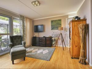 a living room with a chair and a television at Rose Garden in Stevensweert