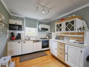 a kitchen with white cabinets and wooden floors at Rose Garden in Stevensweert