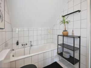 a white bathroom with a tub and a plant on a shelf at Aan de oever in Stevensweert +60 photos