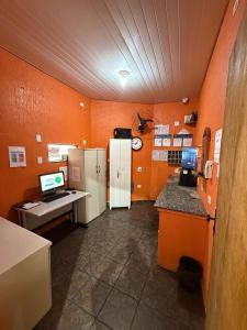 an office with orange walls and a desk and refrigerator at Hotel e Pousada Porto Forte in São Paulo