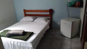 a bedroom with a white bed with a refrigerator at Hotel e Pousada Porto Forte in São Paulo