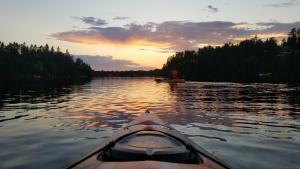 a view from the back of a kayak on a lake at sunset at Refuge Boréal - Bord du lac paisible in Saint-Ambroise +61 photos